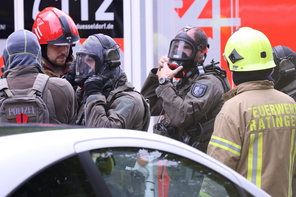 Mehrere Einsatzkräfte von Polizei und Feuerwehr rüsten sich mit Helmen und Schutzmasken aus
