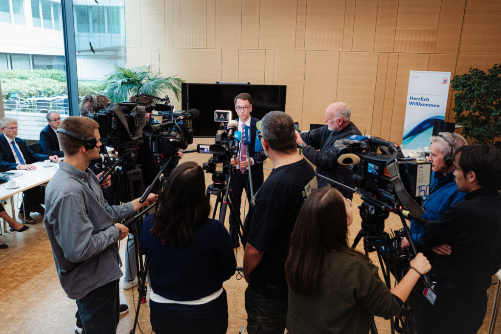 Das Foto zeigt Hessens Justizminister Christian Heinz. Er ist umgeben von Pressevertretern und Kameras.