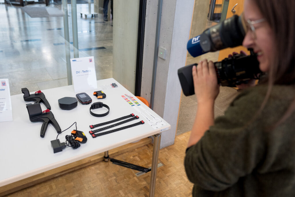 Auf einem Foto filmt eine Kamerafrau Gegenstände. Sie gehören zur Fußfessel-Technik.