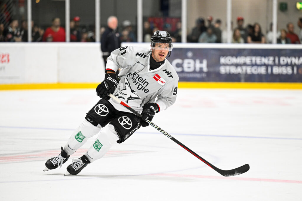 Ein Eishockeyspieler bewegt sich in Schräglage auf dem Eis.