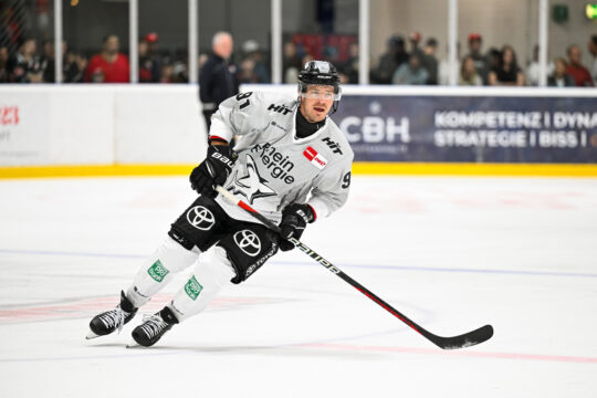 Ein Eishockeyspieler bewegt sich in Schräglage auf dem Eis.